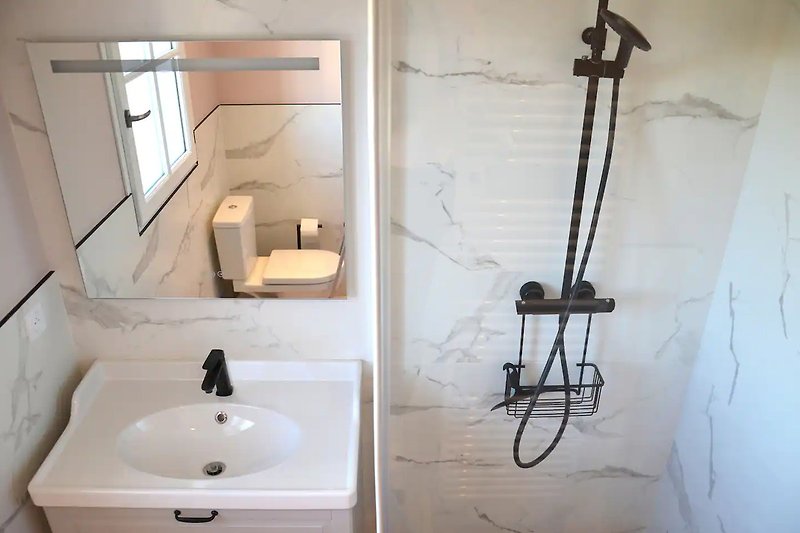 Magnifique salle de bain avec miroir, lavabo et douche en céramique.