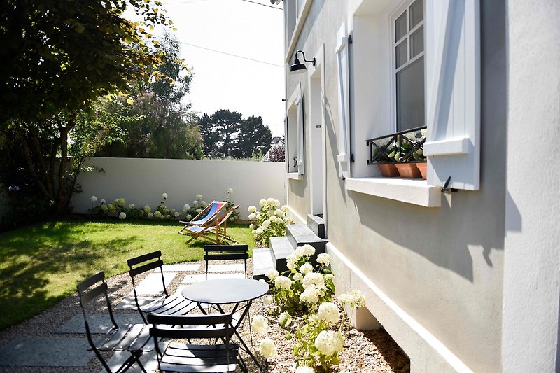 Maison avec jardin, meubles d'extérieur et paysage verdoyant. Vue depuis la terrasse.