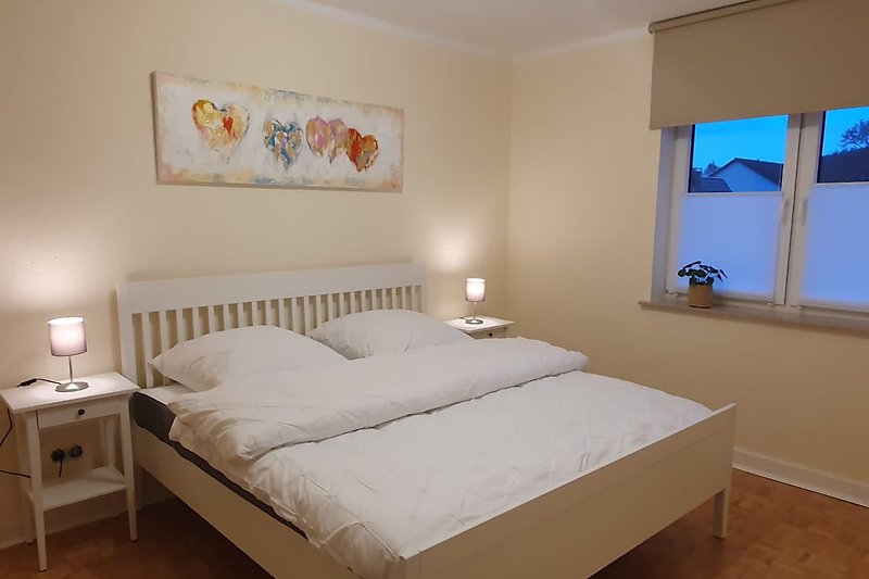 Gemütliches Schlafzimmer mit bequemem Bett, stilvoller Beleuchtung und Holzmöbeln.