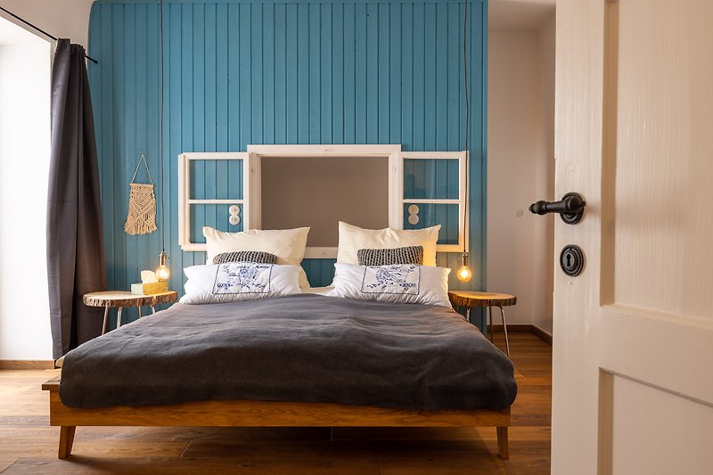 Gemütliches 1. Schlafzimmer mit stilvollem Holzinterieur und bequemem Doppelbett. Hinter der Holzwand ein Einzelbett