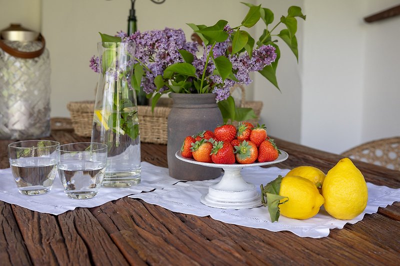 Gemütlicher Tisch mit Blumen, Holzmöbeln und frischen Früchten im Salettl