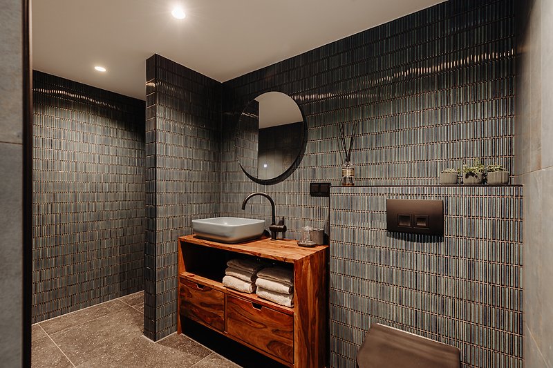 Een stijlvolle badkamer met houten kasten en een mooie wastafel.