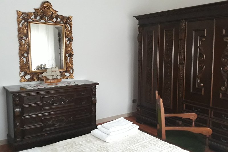 Camera da letto matrimoniale, Specchio e mobili in legno intagliato: un'atmosfera di comfort ed antiquariato italiano