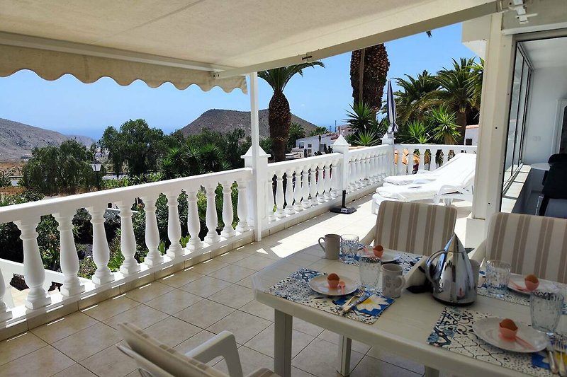 Schöne Terrasse mit stilvollen Möbeln und Blick auf den Garten und Meer.