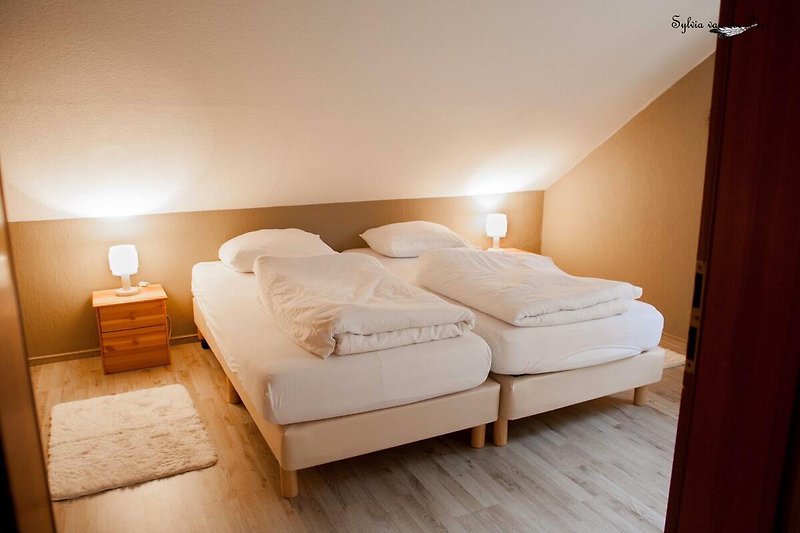Comfortabele slaapkamer met houten meubels en zachte kussens.