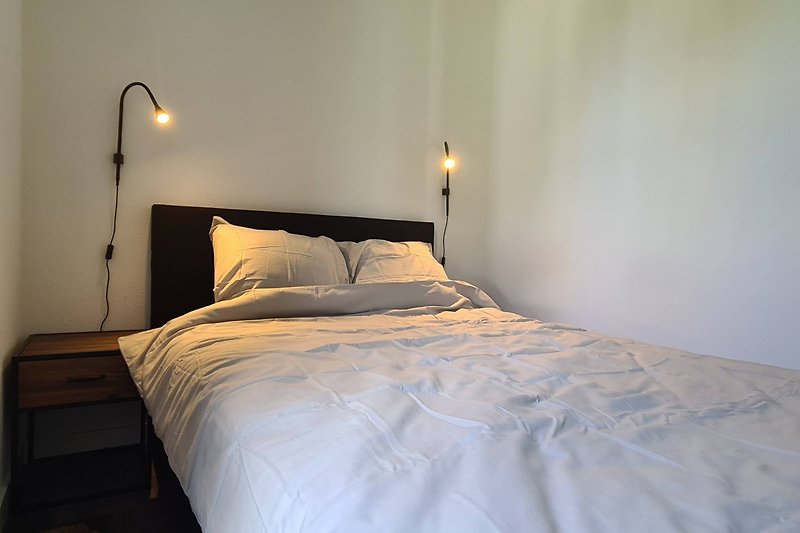 Gemütliches Schlafzimmer mit stilvollem Bett und angenehmer Beleuchtung.