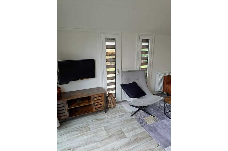 Stilvolles Wohnzimmer mit bequemen Möbeln, Holzboden und großem Fenster.