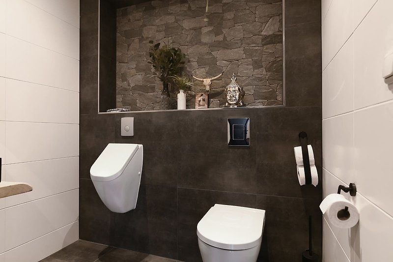 Schwarze Toilette mit Holzverkleidung und stilvoller Armatur.