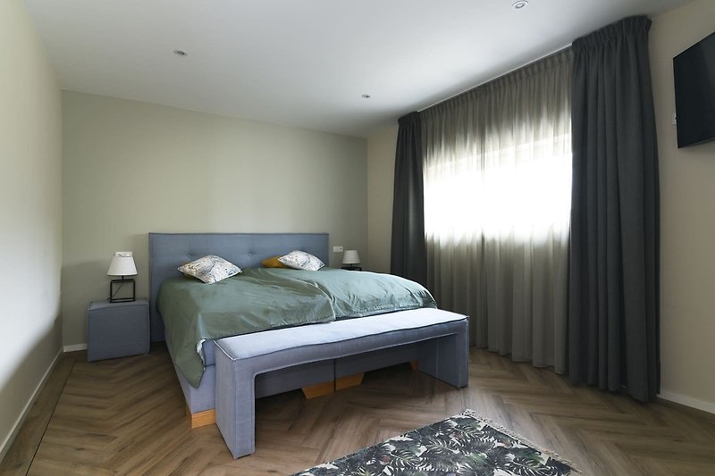 Gemütliches Schlafzimmer mit stilvoller Bettwäsche und Holzbettrahmen.