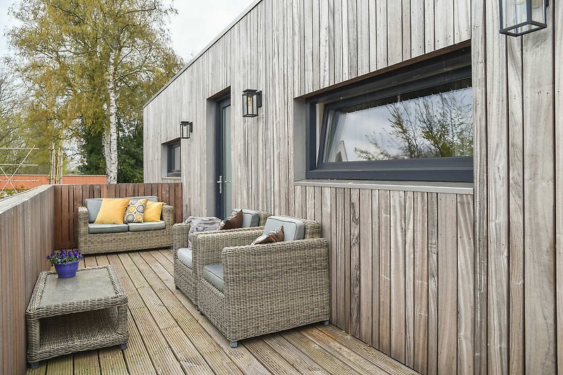 Gemütliches Holzhaus mit schöner Außenmöblierung und grüner Umgebung.