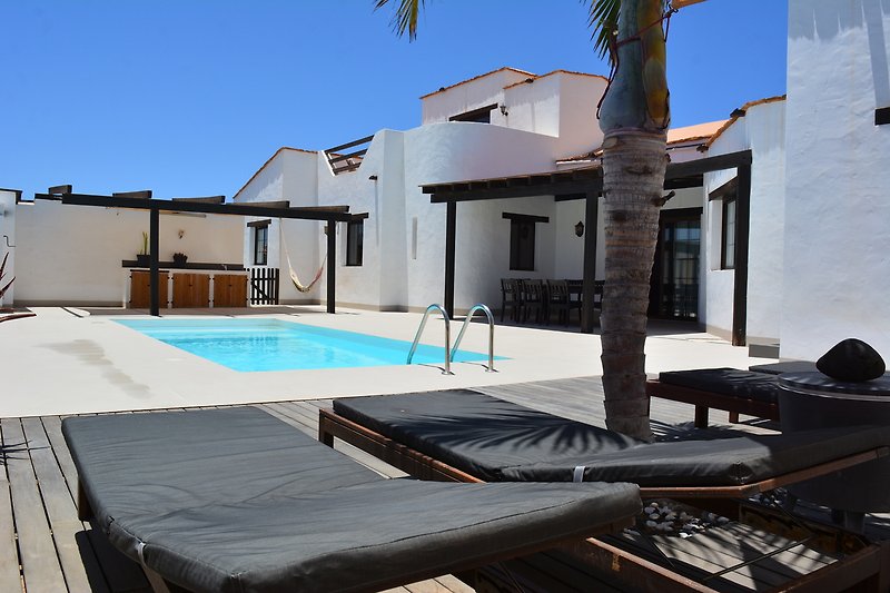 Una piscina azzurra con mobili da esterno e vista sulla proprietà.