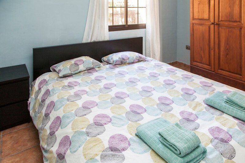 Una camera da letto confortevole con un letto in legno e tessuti viola.