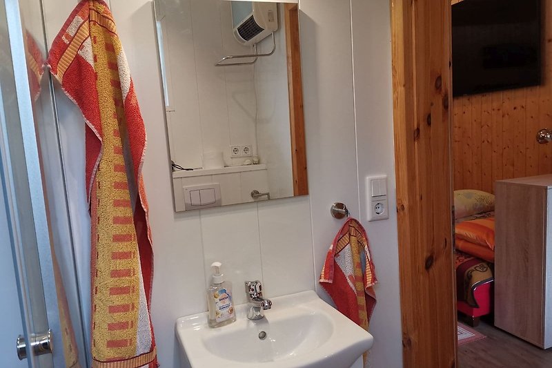 Schönes Badezimmer mit braunem Holz, Spiegel und Waschbecken.