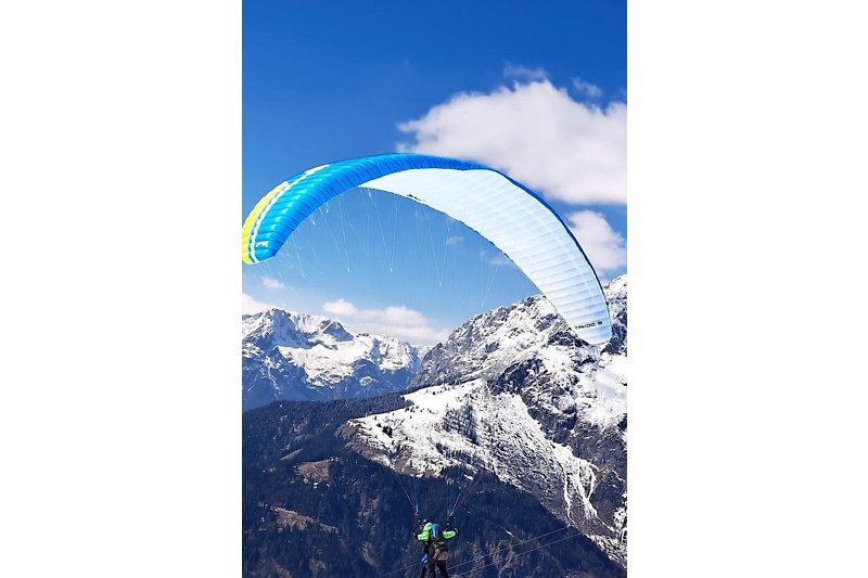 Erleben Sie den Nervenkitzel des Paraglidings in den Bergen. Genießen Sie die atemberaubende Landschaft und den blauen Himmel.