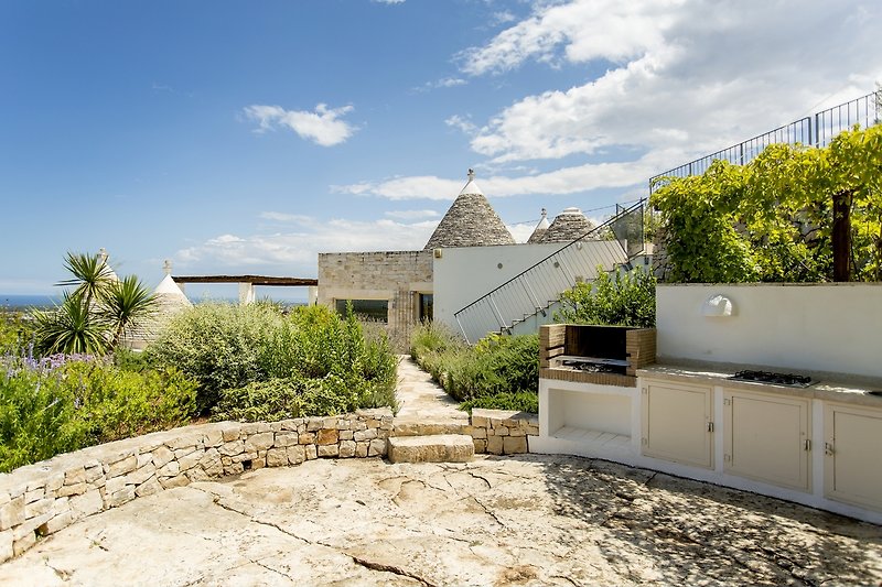 View from dining area towards the outside kitchen and through the gardens to the trullo