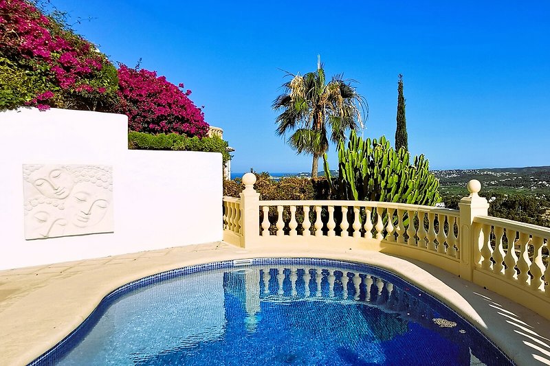 Schöne Villa mit Pool, umgeben von Natur und blauem Himmel.