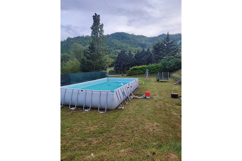 Zelt auf grüner Wiese mit Bergen und Bäumen im Hintergrund.