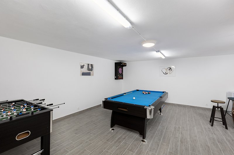 A game room with billiards, table football, and darts.