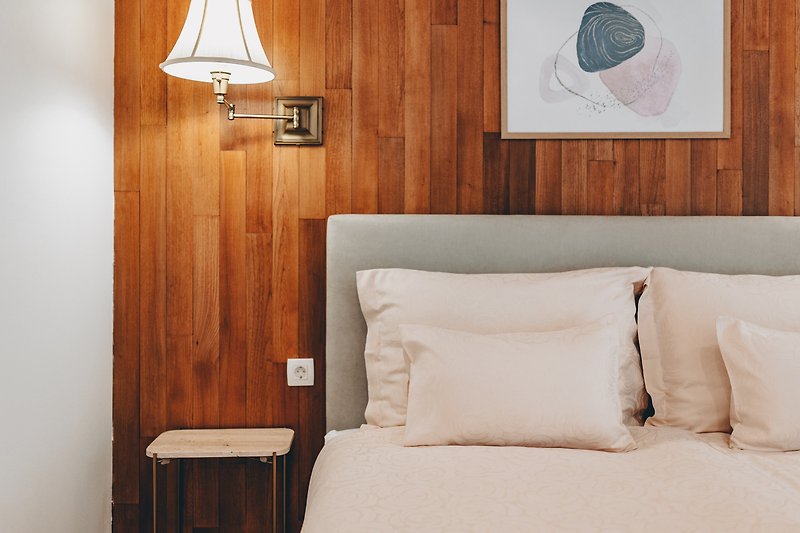 The bedroom with wooden walls exudes a warm and natural ambiance, creating a cozy and inviting atmosphere.