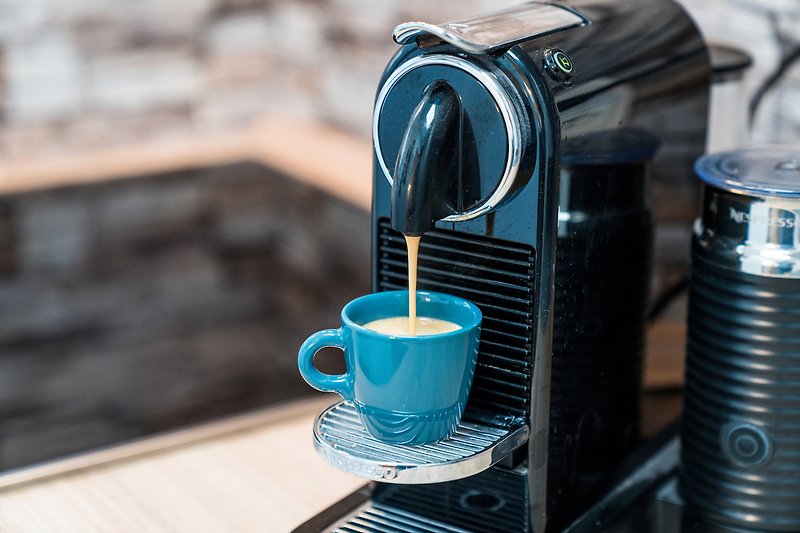 Gemütliche Tasse Kaffee mit blauem Reflex-Kameraobjektiv.