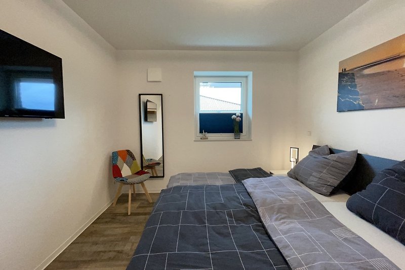 Schlafzimmer 1 mit Doppelbett, Schiebetürenschrank und LED-TV