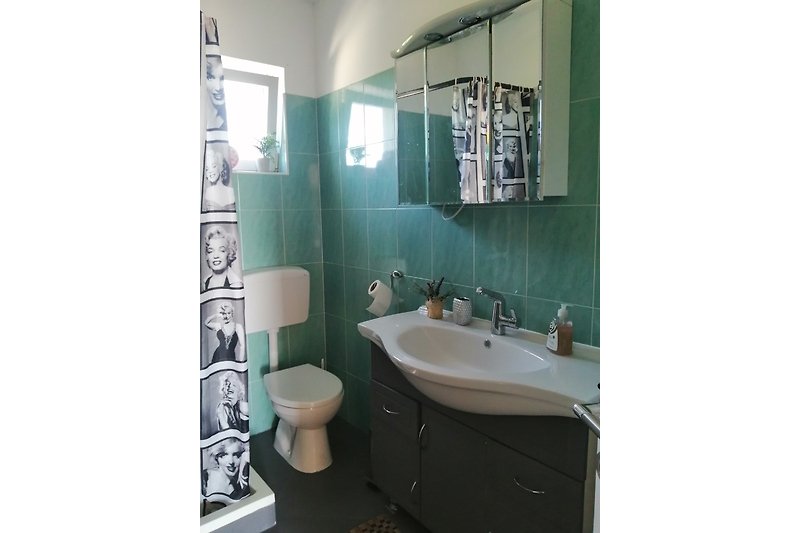 Badezimmer mit lila Badezimmerschrank, schwarzer Armatur und Spiegel.