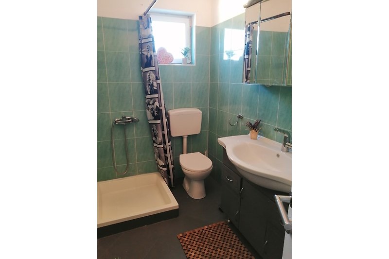 Schönes Badezimmer mit lila Akzenten, Holzboden und stilvollem Waschbecken.