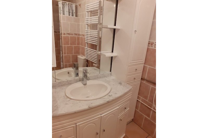 Prachtige badkamer met veel kasten, spiegel en wastafel.