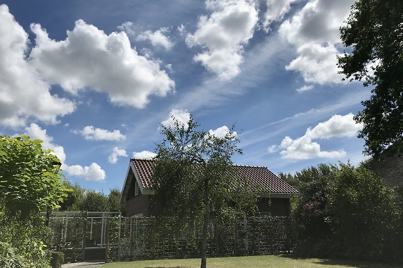 Ein idyllisches Haus mit gepflegtem Garten und ein Holländischer Wolkenhimmel