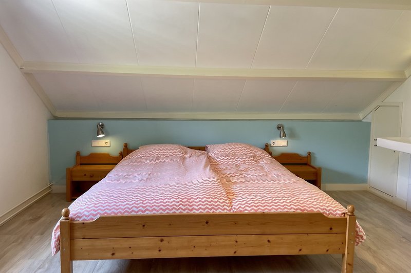 Ein gemütliches Schlafzimmer mit bequemem Bett, Nachschränke und Leselampen.