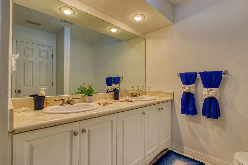 Gemütliches Badezimmer mit lila Waschbecken, stilvoller Beleuchtung und elegantem Spiegel.