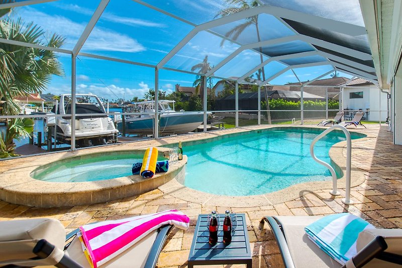 Ferienhaus mit Pool und Palmen in tropischem Resort.