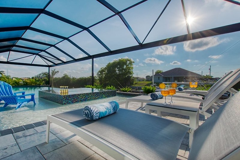 Schwimmbad mit modernem Design, bequemen Möbeln und Blick auf den Himmel.