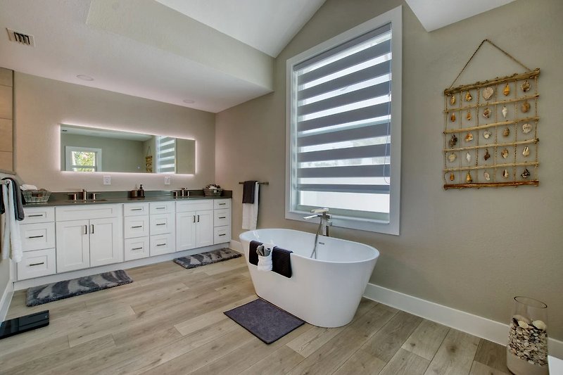 Gemütliches Badezimmer mit weißer Badewanne und Fenster.