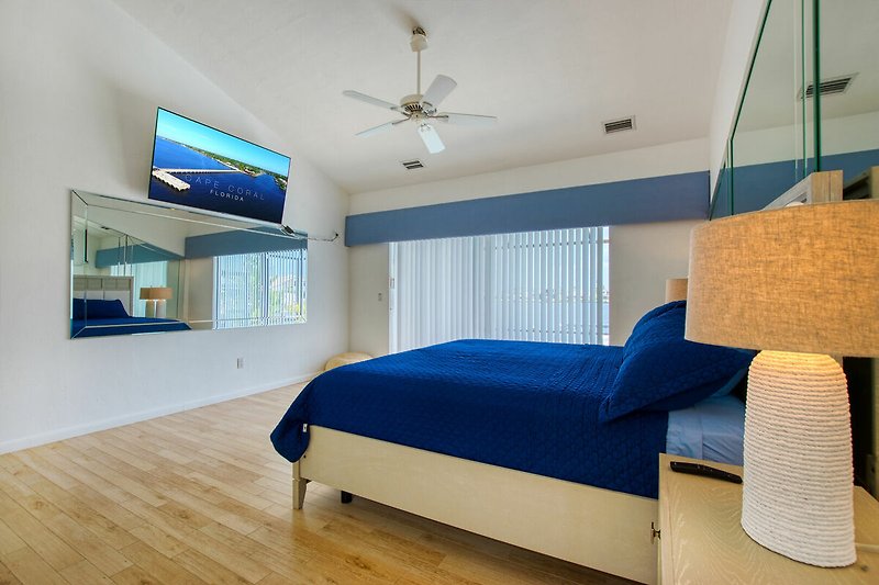 Gemütliches Schlafzimmer mit Holzboden und blauem Bett.