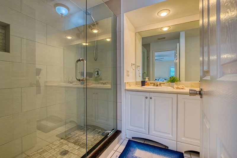 Modernes Badezimmer mit stilvoller Einrichtung, Spiegel und Duschkopf.