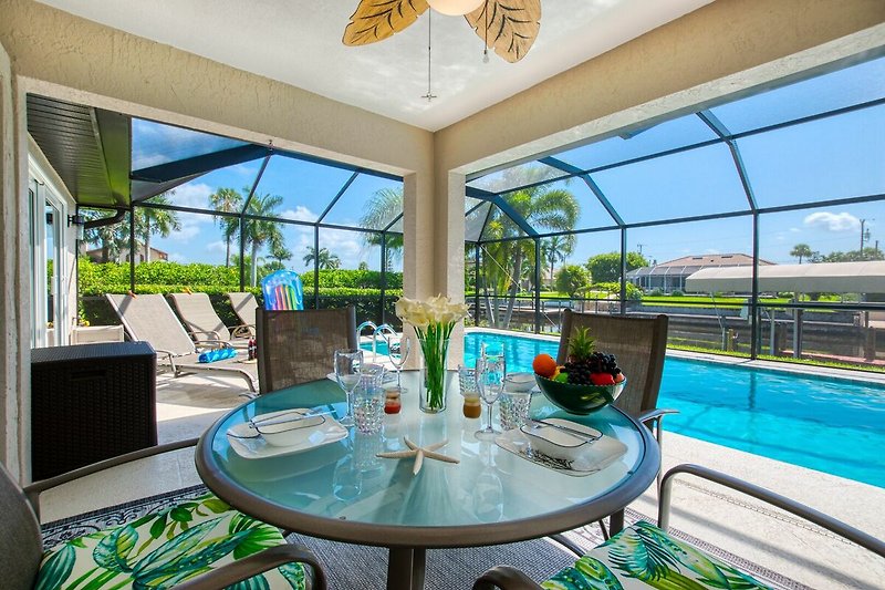 Schöne Terrasse mit Tisch, Stühlen und Blick auf den Pool.
