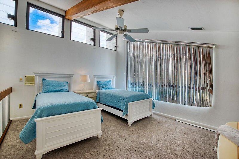 Gemütliches Schlafzimmer mit blauem Bett und Holzmöbeln, gemütliche Beleuchtung.