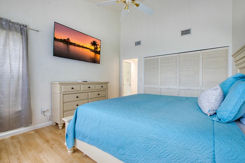 Gemütliches Schlafzimmer mit blauem Bett und Holzmöbeln, gemütliche Beleuchtung