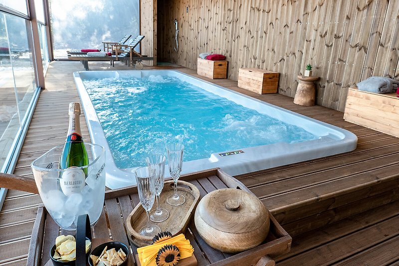 Una piscina rettangolare circondata da mobili da esterno in legno, con una vista panoramica sul paesaggio circostante.