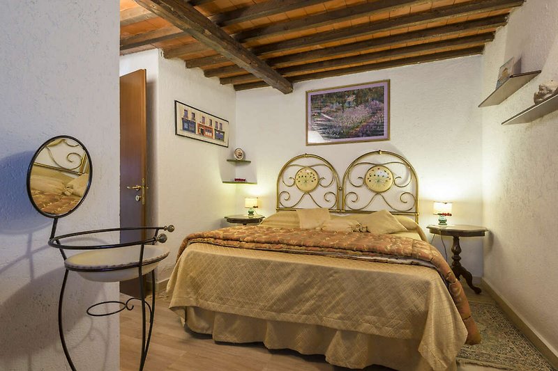 Un'incantevole camera da letto con mobili in legno ed un lucernario che consente di ammirare le stelle del cielo Toscano