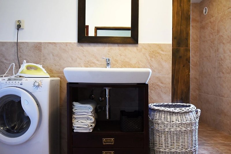 Ein modernes Badezimmer mit Spiegel, Waschbecken und Waschmaschine.