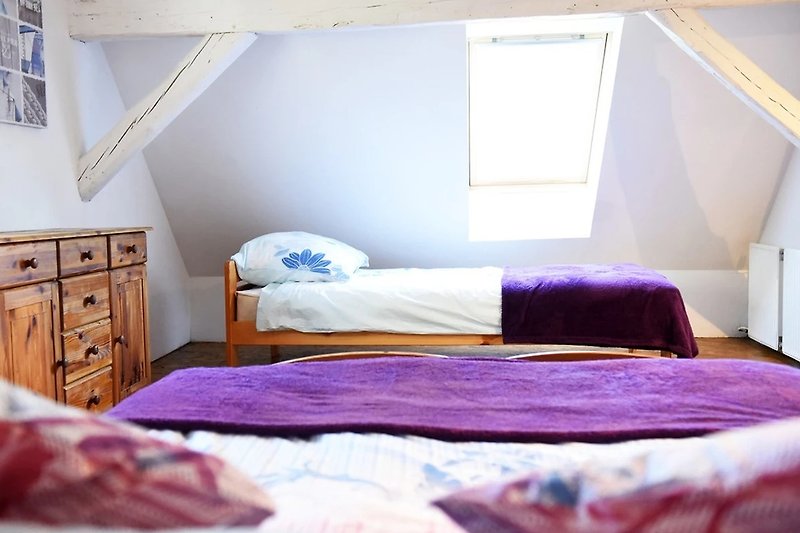 Gemütliches Schlafzimmer mit lila Textilien und Holzmöbeln.