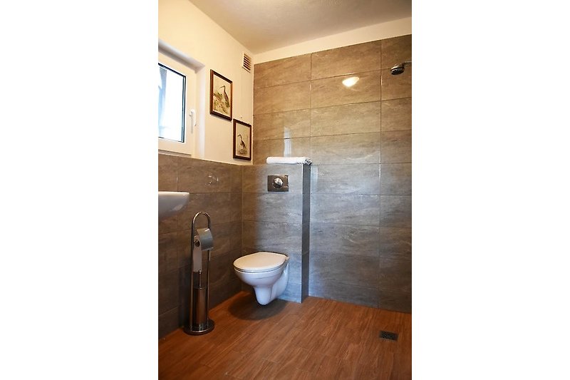 Schönes Badezimmer mit lila Beleuchtung, Holzboden und Keramikwaschbecken.