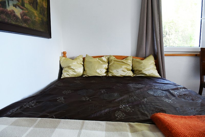Gemütliches Schlafzimmer mit Holzboden, bequemem Bett und Fensterdekoration.