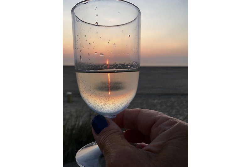 Schöner Sonnenuntergang am Meer mit Weingläsern und Getränken.
