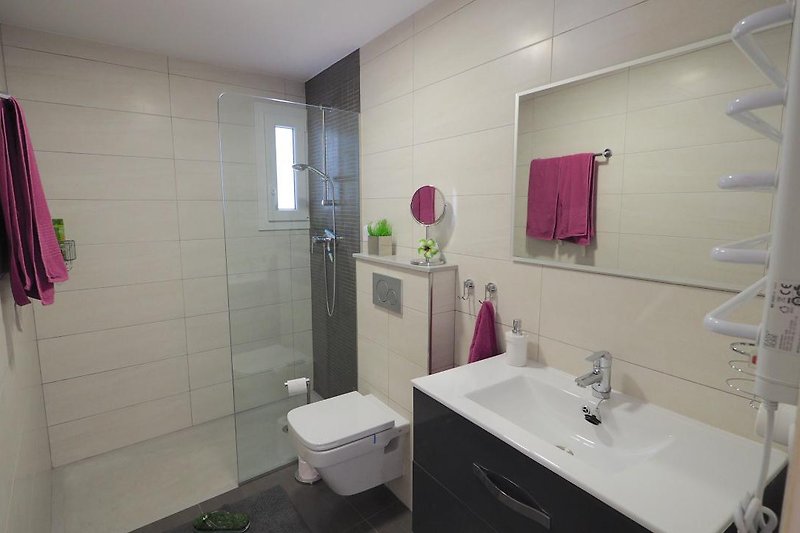 Badezimmer 2 en Suite mit ebenerdiger XXL-Dusche, WC, Waschbecken und Spiegel.