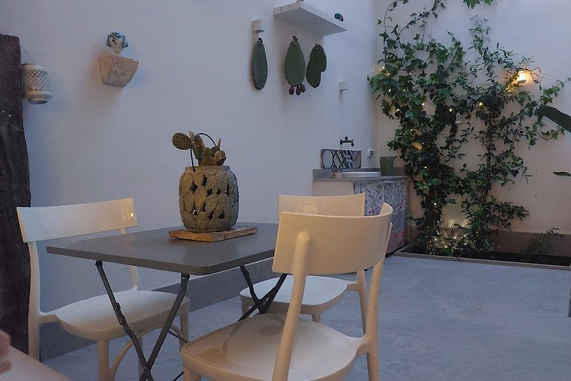 Un tavolo bianco con sedie in legno e una pianta in vaso.