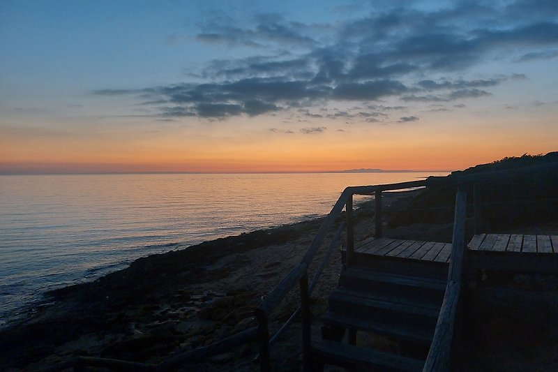 Una vista mozzafiato sul mare al tramonto con nuvole rosse e onde schiumose.