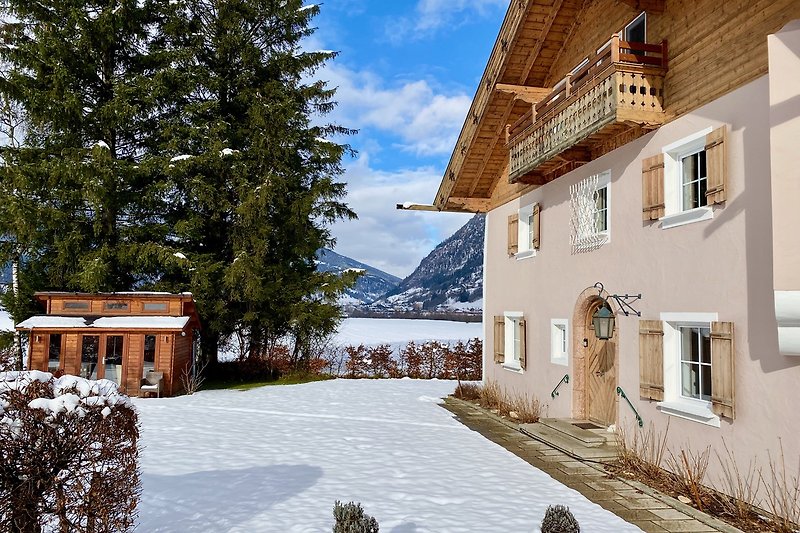 Ein charmantes Haus mit Fenstern, umgeben von verschneiten Bergen und einer malerischen Landschaft.